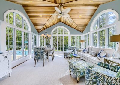 A glorious sunroom with custom wood ceiling and chandelier and multiple windows allowing natural lighting for do I need a general contractor to renovate blog.